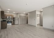 Thumbnail 6 of 18 - an empty living room with a kitchen with a stove and refrigerator