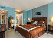 Thumbnail 2 of 26 - A bedroom with a brown bed and a chandelier.