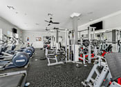 Thumbnail 23 of 37 - A spacious gym with a variety of equipment including treadmills, weights, and a television.