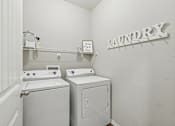 Thumbnail 32 of 37 - A laundry sign is on the wall above a washer and dryer.