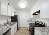 Thumbnail 6 of 14 - A kitchen with black appliances and white cabinets.