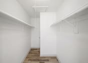 Thumbnail 13 of 14 - A white hallway with a door in the middle and a wooden floor.