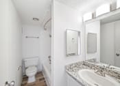 Thumbnail 14 of 14 - A white bathroom with a toilet, sink, and mirror.