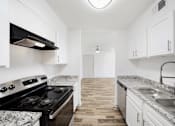 Thumbnail 7 of 14 - A kitchen with a black stove top oven and white cabinets.