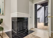 Thumbnail 16 of 25 - A green chair with a white pillow is in front of a fireplace in a room.