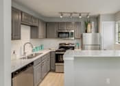 Thumbnail 11 of 25 - A modern kitchen with a white countertop and stainless steel appliances.