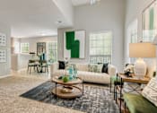 Thumbnail 13 of 25 - A living room with a white couch and a green cushion.