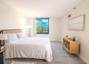 Thumbnail 3 of 14 - A bedroom with a large bed and a window overlooking a green landscape.