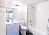 Thumbnail 8 of 14 - A white toilet sits next to a white bathtub in a bathroom.