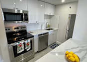Thumbnail 1 of 14 - A modern kitchen with a stove top oven and a dishwasher.