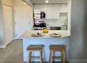 Thumbnail 9 of 14 - A kitchen with a counter and two stools.