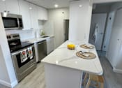 Thumbnail 5 of 14 - A kitchen with a white countertop and stainless steel appliances.