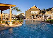 Thumbnail 11 of 37 - A pool in front of a building with a clear blue sky.