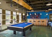 Thumbnail 29 of 47 - a game room with a blue pool table and a bar at Village Club of Rochester Hills, Shelby Township