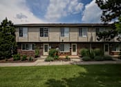 Thumbnail 8 of 47 - an apartment building with a lawn and plants in front of it at Village Club of Rochester Hills, Shelby Township