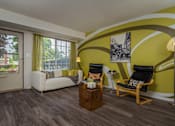 Thumbnail 41 of 47 - a living room with yellow walls and a couch and chairs at Village Club of Rochester Hills, Michigan