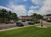 Thumbnail 35 of 47 - a parking lot with cars in front of a building at Village Club of Rochester Hills, Shelby Township Michigan