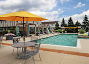 Thumbnail 34 of 47 - our apartments have a pool and patio with chairs and umbrellas at Village Club of Rochester Hills, Shelby Township, 48317