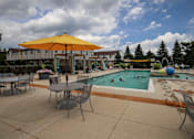 Thumbnail 25 of 47 - a swimming pool with tables and umbrellas and people in it at Village Club of Rochester Hills, Shelby Township, MI 48317