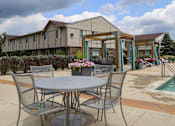 Thumbnail 21 of 47 - a patio with a table and chairs next to a swimming pool at Village Club of Rochester Hills, Shelby Township Michigan