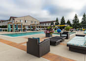 Thumbnail 15 of 47 - a swimming pool with lounge chairs in front of a building at Village Club of Rochester Hills, Shelby Township