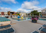 Thumbnail 10 of 47 - a pool with lounge chairs around it and a building with umbrellas at Village Club of Rochester Hills, Michigan, 48317