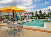 Thumbnail 33 of 47 - our apartments have a swimming pool and patio with chairs and umbrellas at Village Club of Rochester Hills, Shelby Township, MI