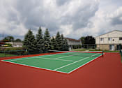 Thumbnail 30 of 47 - a tennis court with a house and trees in the background at Village Club of Rochester Hills, Michigan