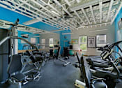 Thumbnail 26 of 47 - a gym with various exercise equipment in a building with blue walls at Village Club of Rochester Hills, Shelby Township, MI