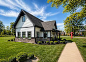Thumbnail 2 of 18 - A white house with a black roof and a red flag on the lawn.