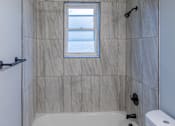 Thumbnail 10 of 10 - A bathroom with a tub, toilet, and sink.
