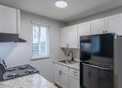 Thumbnail 4 of 10 - A kitchen with a stove, sink, and refrigerator.