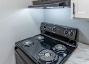 Thumbnail 6 of 10 - A black stove top with four burners and knobs.