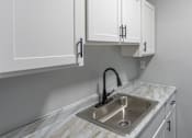 Thumbnail 9 of 10 - A kitchen with a marble countertop and a stainless steel sink.