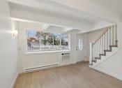 Thumbnail 4 of 33 - A spacious room with a staircase and a window overlooking a street.