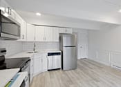 Thumbnail 6 of 33 - A modern kitchen with white cabinets and a wooden floor.