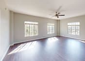 Thumbnail 9 of 25 - A spacious room with wooden floors and a ceiling fan.