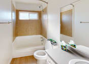 Thumbnail 10 of 12 - A white bathroom with a toilet, sink, and bathtub.
