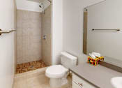 Thumbnail 11 of 12 - A white toilet sits next to a walk-in shower in a bathroom.