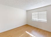 Thumbnail 8 of 12 - A room with a window and wooden flooring.