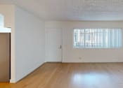 Thumbnail 6 of 12 - A room with a wooden floor and a window with blinds.