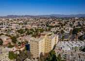 Thumbnail 20 of 25 - A cityscape with a large building in the center and a mountain range in the distance.