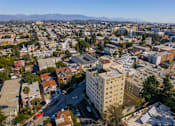 Thumbnail 22 of 25 - A cityscape with a large white building in the center and a mountain range in the background.