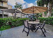 Thumbnail 44 of 46 - A patio with a table and chairs under an umbrella.