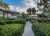 Thumbnail 42 of 46 - A pathway leads through a landscaped courtyard with a pavilion in the background.
