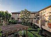 Thumbnail 40 of 46 - A wooden deck is in the middle of a grassy area with a building in the background.