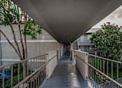Thumbnail 45 of 46 - A long concrete walkway with a metal railing on both sides.