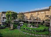 Thumbnail 43 of 46 - A building with a green lawn and a tree in front of it.