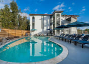 Thumbnail 1 of 11 - a swimming pool with lounge chairs and a building in the background