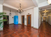 Thumbnail 5 of 25 - A blue recycling bin sits in the middle of a room with a chandelier hanging from the ceiling.